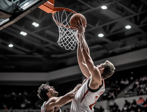A basketball player in a white jersey is dunking a ball into the hoop, with an opposing player closely contesting. The action is intense and dynamic.